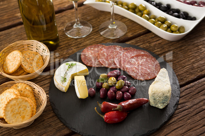 Close-up of marinated olives with bottle of wine and food