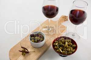 Close-up of marinated olives with glasses of wine