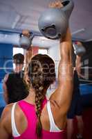 Rear view of young female athlete lifting kettle