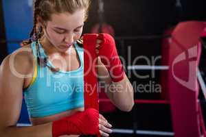 Young female athlete wrapping red bandage on hand