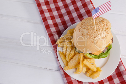 Burger decorated with american flag and french fries in plate