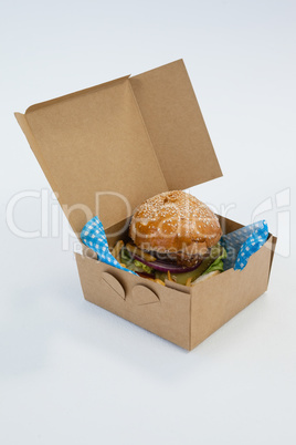 Hamburger in a take away container on table