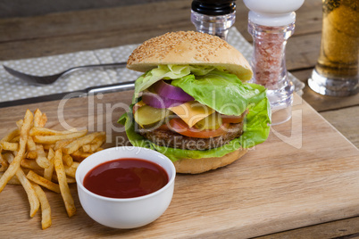 Hamburger, french fries and tomato sauce on chopping board