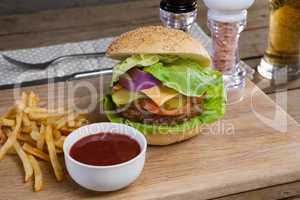 Hamburger, french fries and tomato sauce on chopping board