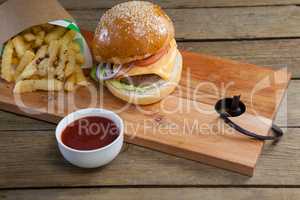 Hamburger, french fries and tomato sauce on table