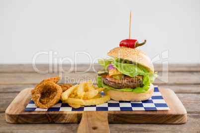 Close up of hamburger with onion rings and french fries