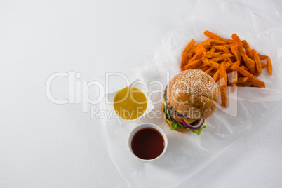 Hamburger by French fries and dips in bowl