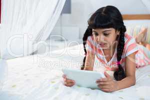 Girl using tablet while lying on bed at home
