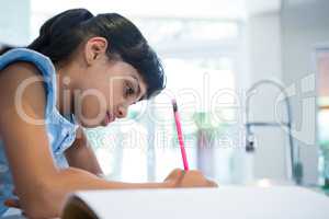 Side view of girl writing in book