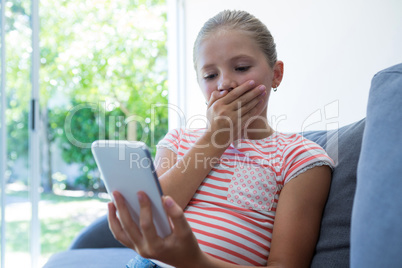 Girl with hands covering mouth holding phone