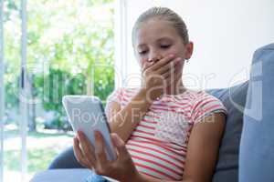 Girl with hands covering mouth holding phone