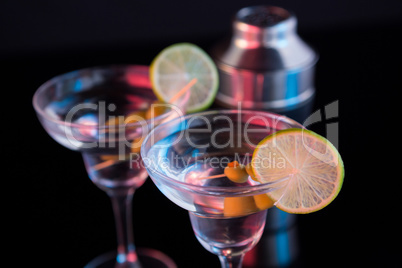 Cocktail martini with olives and shaker on table