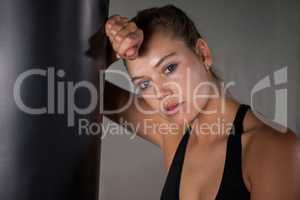 Exhausted female boxer leaning on punching bag