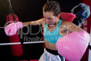 Young female boxer sitting in corner of boxing ring