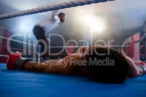 Unconscious boxer lying by referee in ring