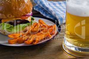 Burger and french fries in plate with glass of beer