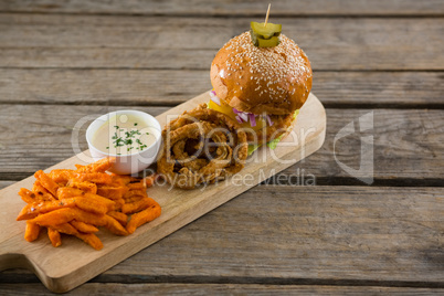High angle view of hamburger by onion rings with dip and french fries