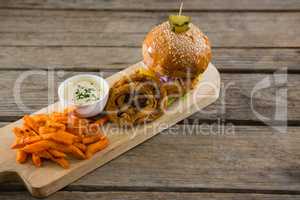 High angle view of hamburger by onion rings with dip and french fries