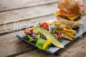 Close up of salad with french fries and burger