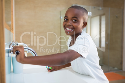 Side view portrait of smiling boy with toothbrush looking at mirror