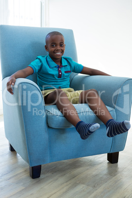 Portrait of happy boy sitting on armchair at home