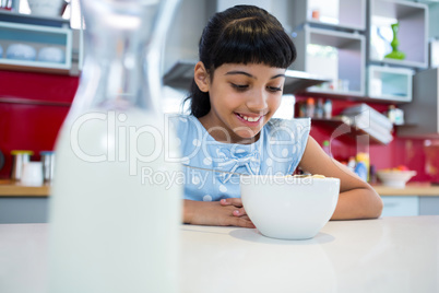 Smiling girl looking at breakfast in bowl