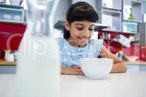 Smiling girl looking at breakfast in bowl