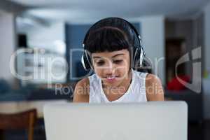 Girl using laptop while listening music from headphones