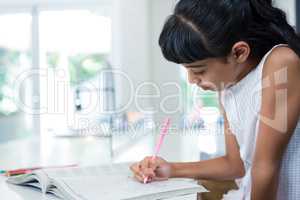 Side view of girl drawing in book