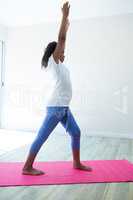 Side view of girl with arms raised exercising in room