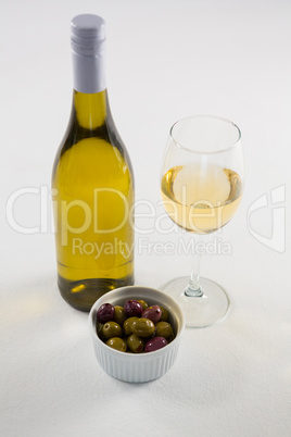 Close-up of marinated olives with glass and bottle of wine