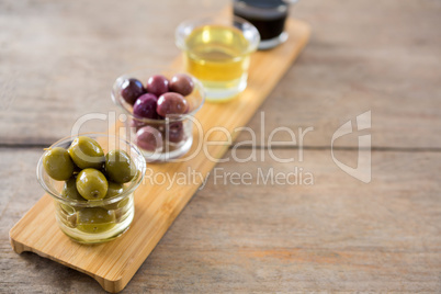 Marinated olives with olive oil and balsamic vinegar in glass container on a wooden tray