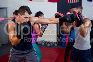 Male boxer and instructor practicing with boxing