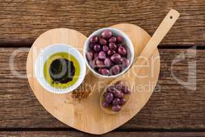 Purple olives, oil and wooden spoon on table