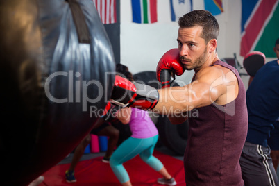 Young male boxer punching black bag