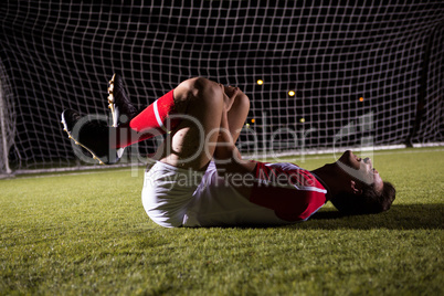 Side view of young male soccer player suffering from knee pain