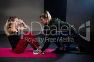 Trainer assisting woman in exercise
