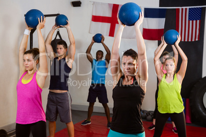 Young athletes holding exercise balls with arms raised