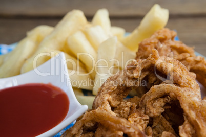 Onion ring and french fries with ketchup arranged in plate