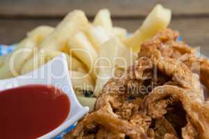 Onion ring and french fries with ketchup arranged in plate