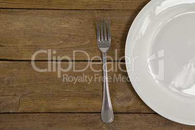 White plate and fork on wooden table