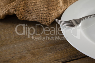 White plate and fork on wooden table