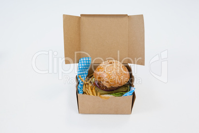 Hamburger and french fries in a take away container on table