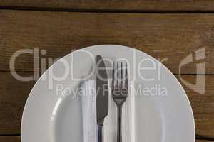 White plate with cutlery and napkin on table