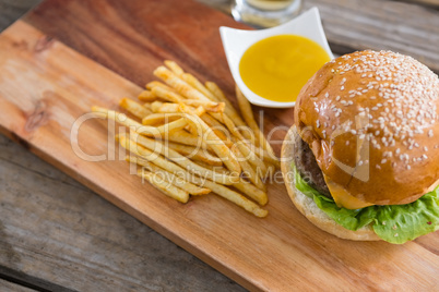 Hamburger with fries and dip on cutting board