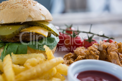 Close up of burger and fries with onion rings by sauce