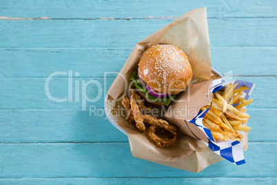 Overhead view of burger with french fries and onion rings in container