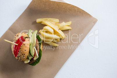Overhead view of burger with French fries on paper