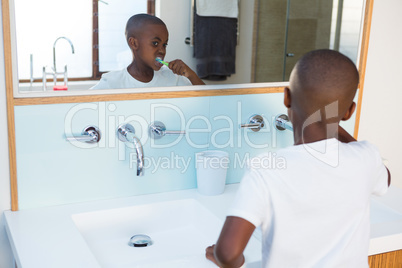Boy brushing teeth looking at mirror reflection