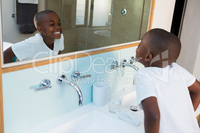 High angle view of boy clenching teeth while looking at mirror